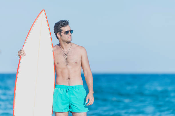 istock Young attractive surfer holding his surfboard at the beach 966419426