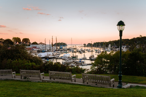 Wooden Benches along a Path in a Waterfront Park facing a Beautiful Harbour full of Moored Boats at Twilight. Camden, ME, United States.
