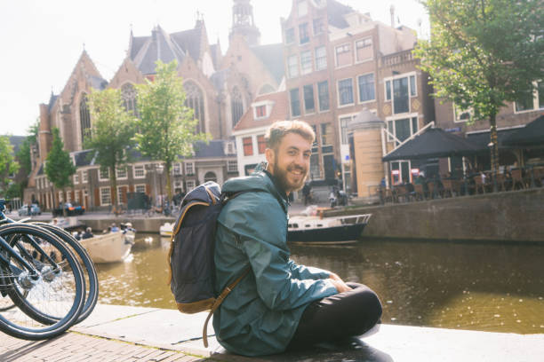 istock Man sitting at the canal in Amsterdam at sunset 966422418