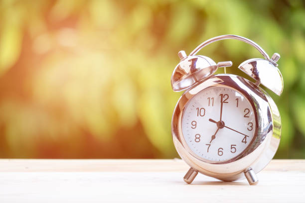 istock alarm clock on table on nature green background 966431060