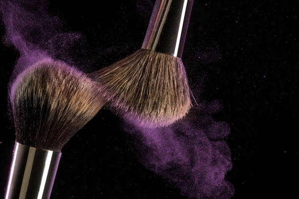 istock Make-up brush concept with ultraviolet powder explosion isolated on black background. 966438332