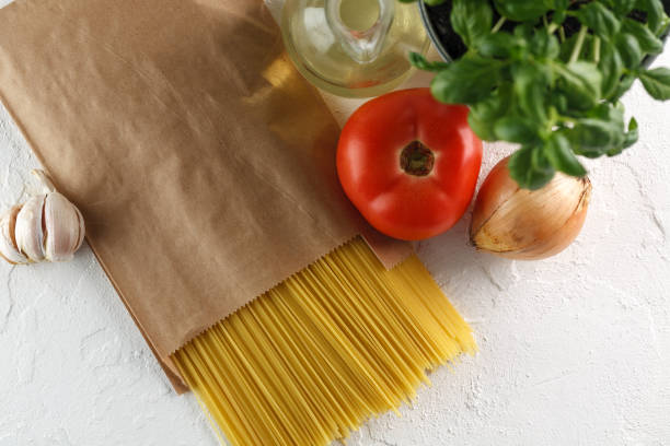 istock raw italian pasta spaghetti with vegetables on white background. Top view. Copyspace 966474776