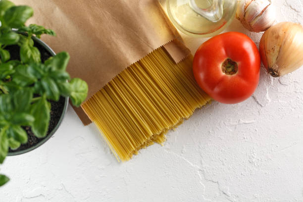 istock raw italian pasta spaghetti with vegetables on white background. Top view. Copyspace 966474828