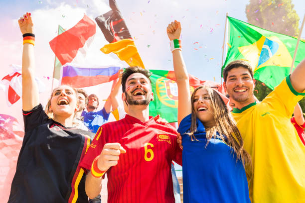 Happy supporters from different countries together at stadium. Fans from France, Germany, Spain, Brazil and other countries enjoying a match together. Sport, achievement and success concepts