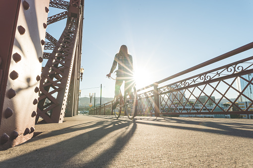 Beautiful blonde woman rides her bicycle across the bridge on a summer afternoon