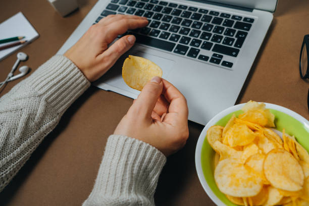 istock Woman hands with chips and laptop on brown background. Top view. Flat lay 966498234