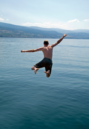 A boy jumps from jetty into the sea in summer. Taken in the Marlborough Sounds of New Zealand's South Island.