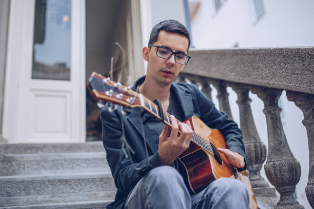 istock Young man with differing abilities playing acoustic guitar outdoors 966501906