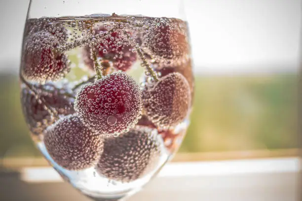 Cherry in soda water with bubbles.lemonade ice water with tasty raw berries, red cheriies. Copy space