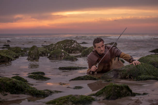 istock Weapon wielding bloody medieval warrior alone on a cold seashore at sunset 966517704