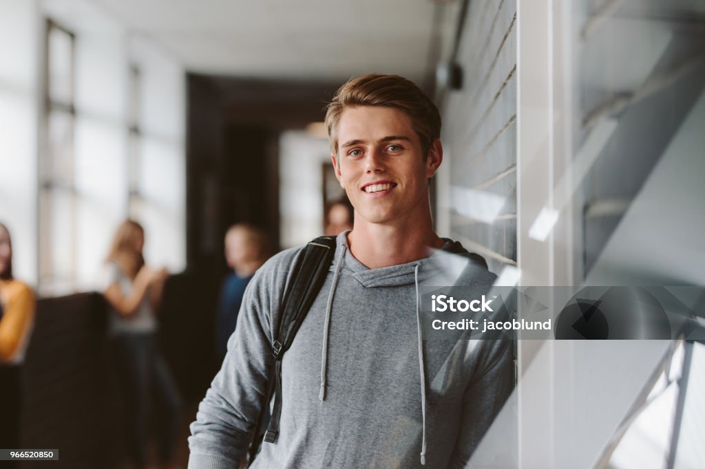 University student in campus Portrait of teenage male student standing wall in corridor of a college. Caucasian male student in university campus. Teenager Stock Photo