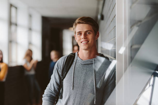 University student in campus Portrait of teenage male student standing wall in corridor of a college. Caucasian male student in university campus. teenage boys stock pictures, royalty-free photos & images