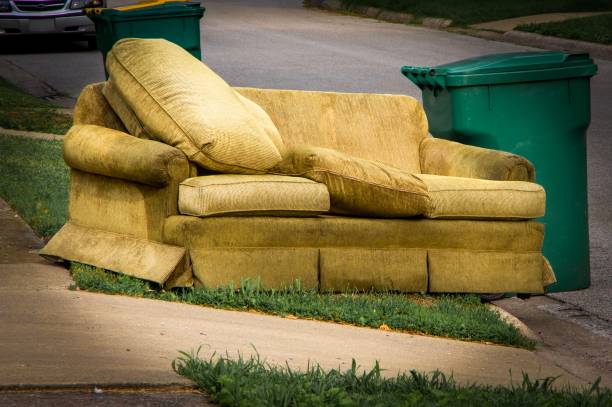 Old couch sitting along curb beside garbage container on trash day Furniture placed for bulk trash disposal in residential neighborhood curb photos stock pictures, royalty-free photos & images