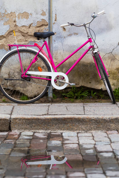 istock Open frame ladies bicycle parked at old cracked worn wall and its reflection in puddle on a pavement. 966526740