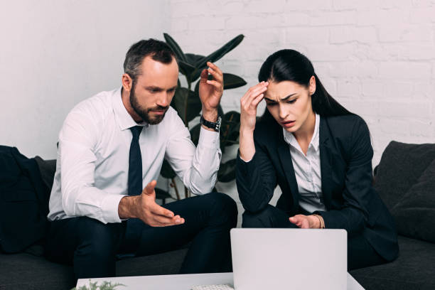 istock stressed business colleagues working on laptop together at coffee table in office 966527598