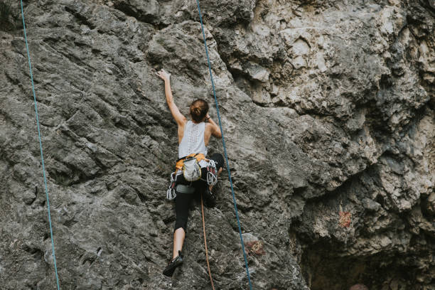 Focused young female climber, climbing up alone stock photo
