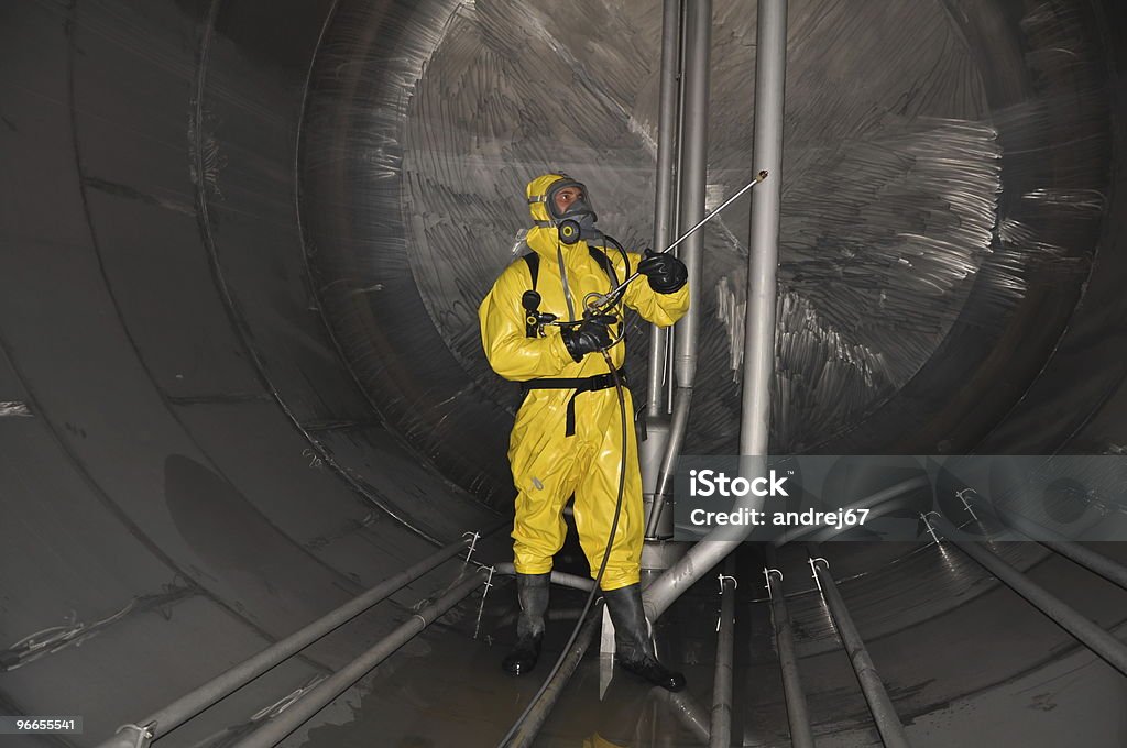man in chemical suit man in chemical suit inside  cargo tank on deck of chemical tanker for cleaning operation Cleaning Stock Photo