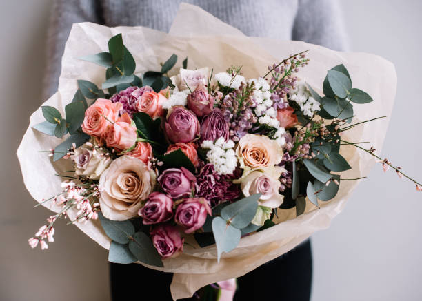 若い花屋女性たてを保持は、灰色の壁の背景にバラとユーカリの花の花の花束を作りました。 - bouquet rose wedding flower ストックフォトと画像