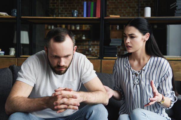 istock depressed young man sitting on couch and looking away while his wife pressing him 966564376