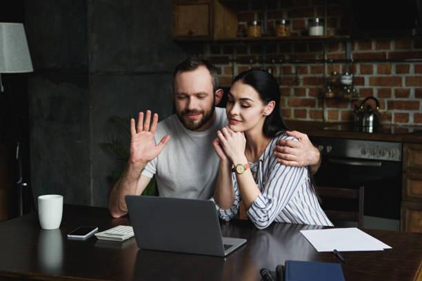 istock happy young couple making video call with laptop at kitchen 966566988