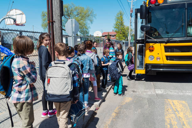 istock Kids in line waiting to get on school bus. 966571738