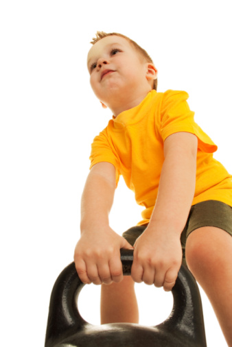 Little boy tries to lift greater weight. Isolated on white.