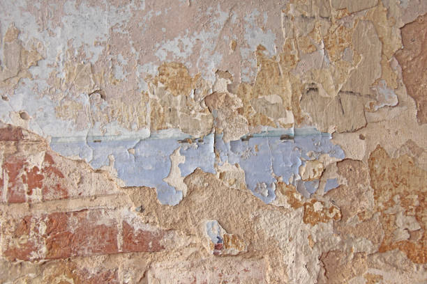 istock Old flaky white paint peeling off a grungy cracked wall. Cracks, scrapes, peeling old paint and plaster on background of old cement wall. An old cement stone wall as vintage cracked. Brick wall. 966618512