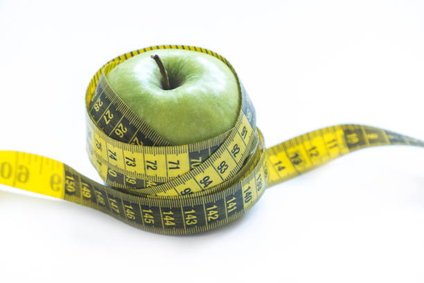 Green apple with yellow measuring tape diet concept