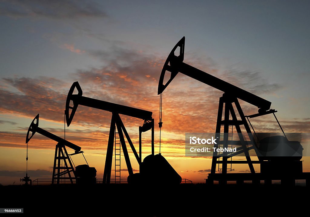 Silhouette three oil pumps Three pumps over orange sky Black Color Stock Photo