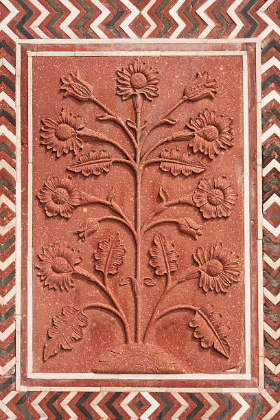 Agra, India - March 11, 2024: The Taj Mahal mausoleum is seen from the side with two marble minarets, groups of people walking and standing on the marble platform, and a flower bed in the foreground under a partly cloudy sky.