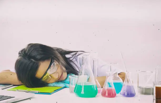 The abstractart design background of the chemist in protective eyeglasses working by test tube with reagent in lab,she is sleeping with streess and tried from hard work in lab.