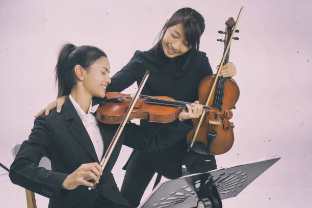 istock The violin teacher is teaching the violin student,put hands to student shoulder for the encourage together,violin class,at studio music room. 966715190