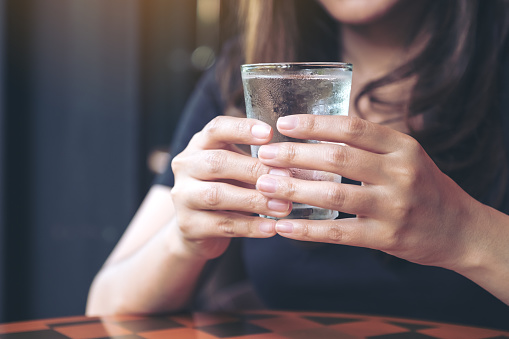 Closeup image of woman holding a glass of cold water to drink