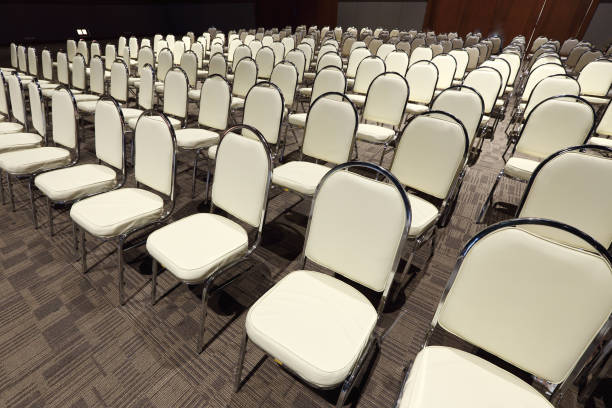 Many White PU Chairs arranged in row order for Performance Contest in Ballroom Hotel, Multiple Portable Seats set up for Conference meeting in Business Seminar of Company, Copy space for text logo