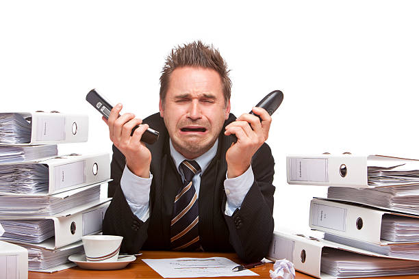 Stressed business man with telephones cries frustrated in office stock photo