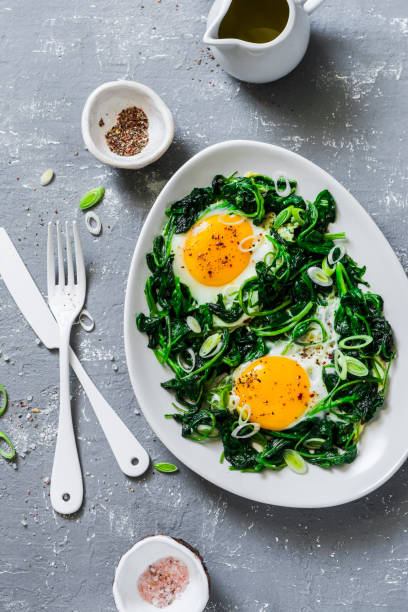 istock Fried eggs with spinach - healthy diet breakfast on a gray background. Top view 966761434