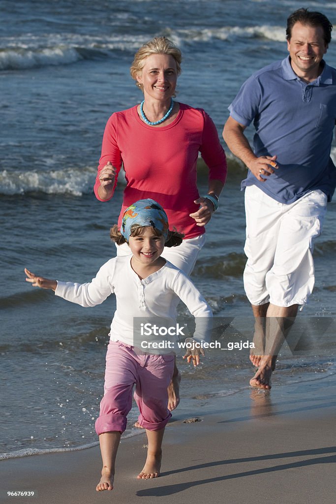 Una famiglia che gioca sulla spiaggia - Foto stock royalty-free di Adulto