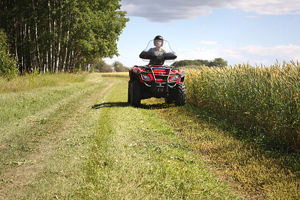 Teen on all terrain vehicle in field stock photo