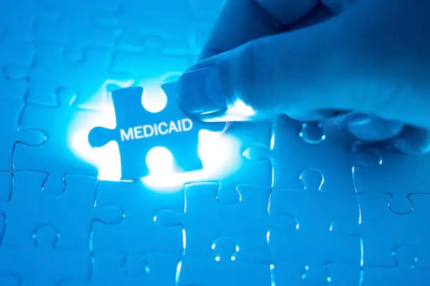 Photo of Health Care Concept. Doctor holding a jigsaw puzzle with MEDICAID word.