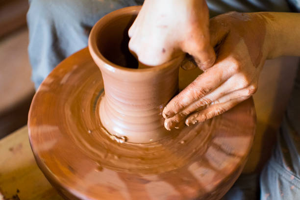 istock hands of a potter, creating an earthen jar on the circle 966786718