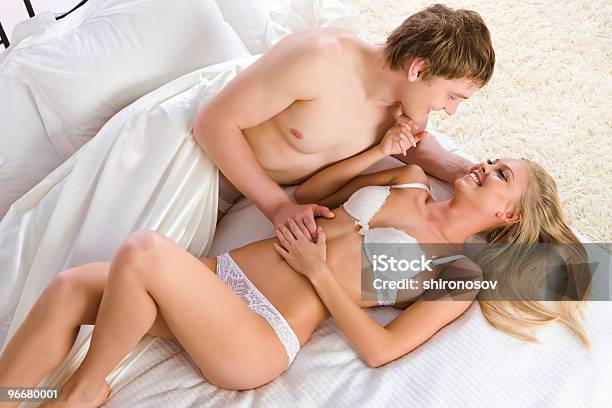 A Scantily Clad Smiling Couple Laying Together On A Bed Stock Photo - Download Image Now