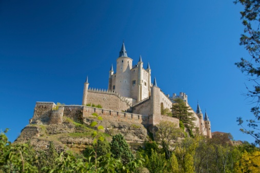 landmark monument public castle quarterdeck fortress from year 1122 dome cone architecture in travel destination Segovia city Spain Europe between trees green forest blue sky
