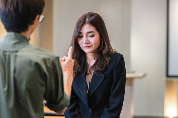 reaw vue de furious patron gronder asiatique jeune femme d’affaires en costume officiel de pointer vers son visage dans les bureaux modernes, erreur de business et punir concept - point de pression photos et images de collection