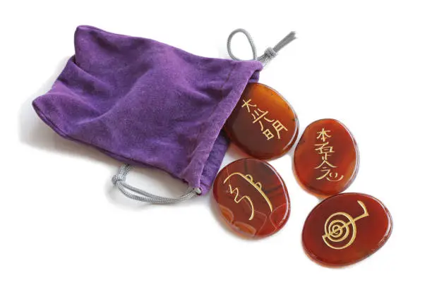 four carnelian stones gold etched with the four main Reiki Symbols isolated on a white background