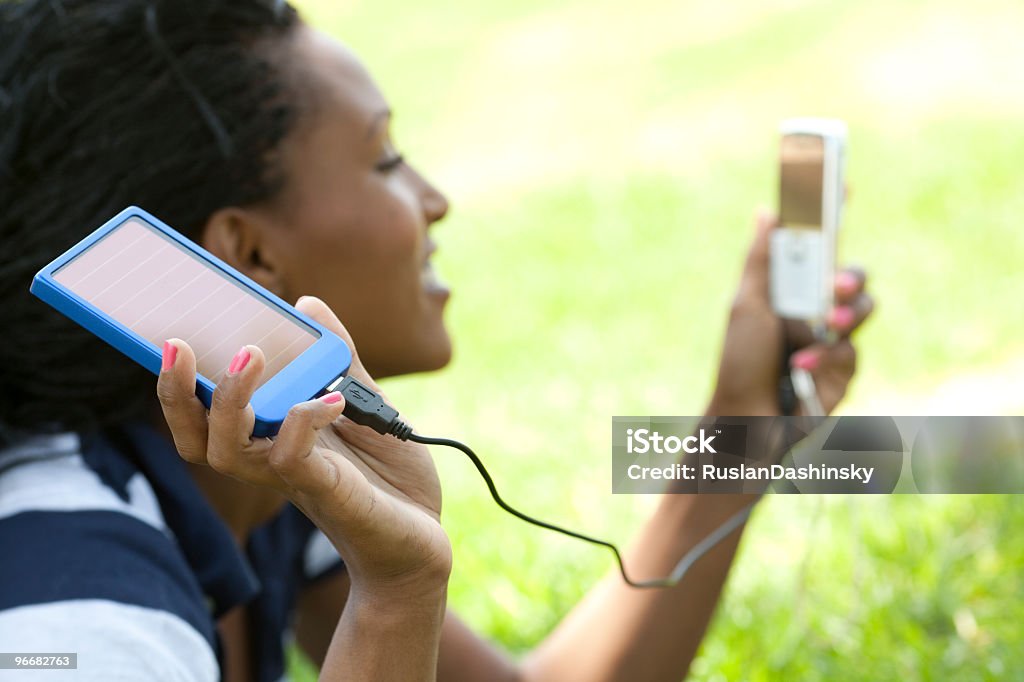 Use green energy -  solar charger Young woman uses solar charger panel to charge her cellphone. Solar Energy Stock Photo