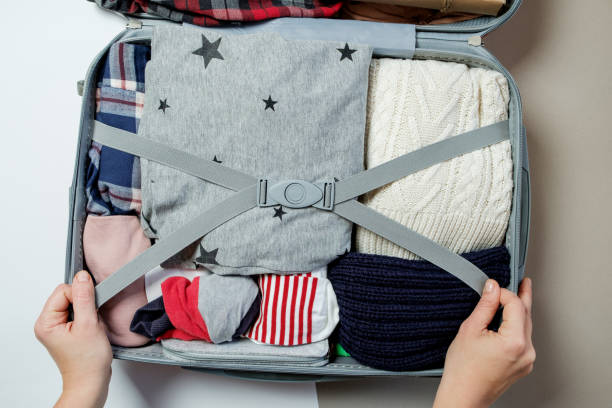 istock Female hands packed clothes in suitcase. Winter vacations and holidays. Top view 966836582
