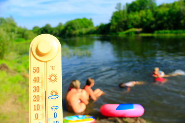 istock Thermometer with indication 31 degrees and bathing people in river. It is hot outside 966839958