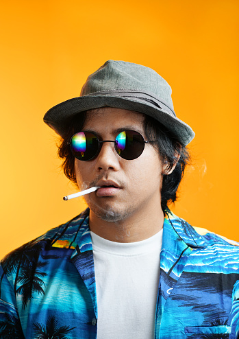 Hawaiian Gangster Smoking a Cigarette Wearing Fedora Hat and Sunglasses against Yellow Background