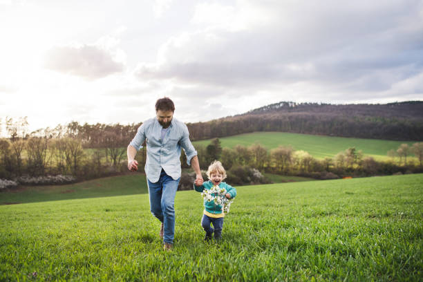 istock A father with his toddler son running outside in spring nature. 966841114