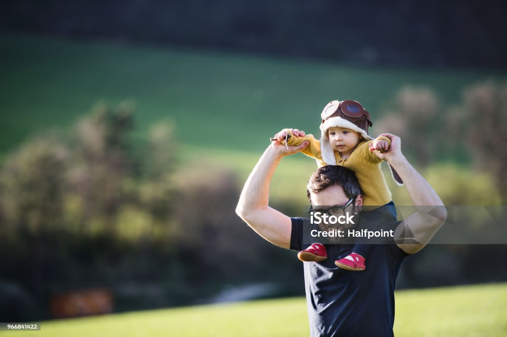 A father with his toddler daughter outside in spring nature. A handsome father with his toddler daughter outside in green sunny spring nature. Copy space. Father Stock Photo